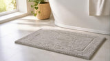 Silver grey Willow & Fern cotton bath rug on a light bathroom floor beside a freestanding tub