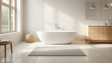 Silver grey cotton bath rug on a light bathroom floor beside a tub and wooden vanity