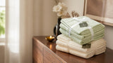 Folded sage green and off white Willow & Fern towel sets tied with ribbon beside a brass diya, a Diwali gift idea