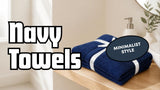 Folded navy blue cotton towels tied with a ribbon on a light oak bathroom shelf