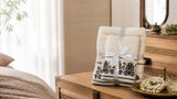 Folded Willow & Fern embroidered cotton towel set tied with a ribbon on a wooden chest in a bright bedroom