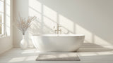 Grey cotton bath rug on a bright bathroom floor in front of a freestanding white tub