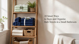 Folded Willow and Fern sage green and navy cotton bath towel sets stored on a wooden ladder shelf in a small modern bathroom