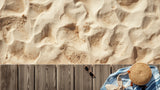 Blue and white striped cotton beach towel on a wooden pool deck beside a straw tote and sunglasses