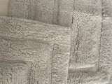 Silver grey cotton bath rug lying flat on a bathroom floor